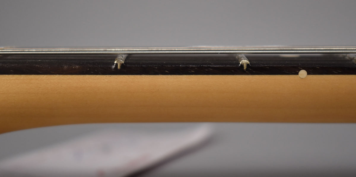 Close-up of the guitar's neck, showing the dark fretboard, light maple neck, two frets, and a single dot inlay.