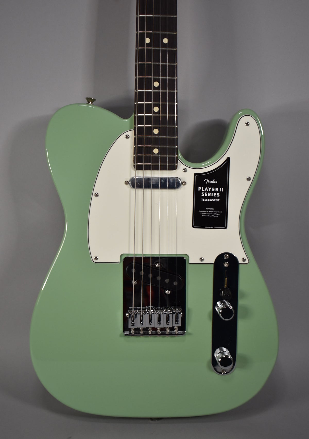 Full front view of a glossy birch green Telecaster with a white pickguard, chrome hardware, and a black control plate.