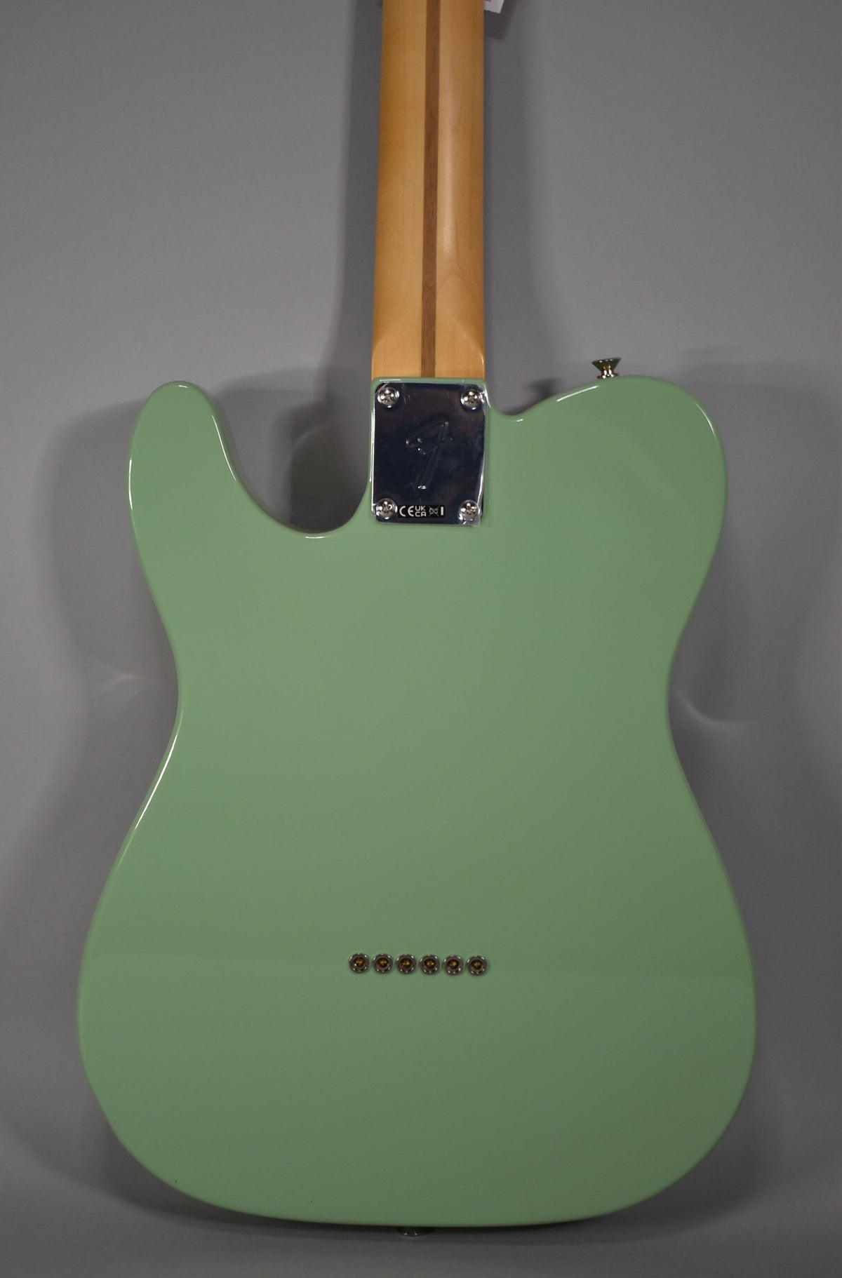 Full rear view of a glossy birch green Telecaster, showing the maple neck, chrome neck plate, and six string ferrules.