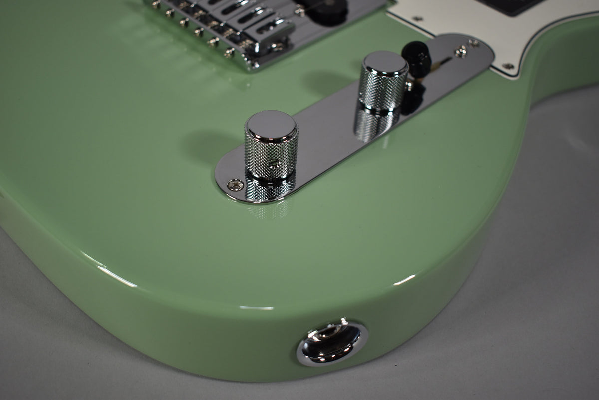 Close-up of the guitar's lower body, showing the glossy birch green finish, chrome control plate with two knurled knobs, and output jack.