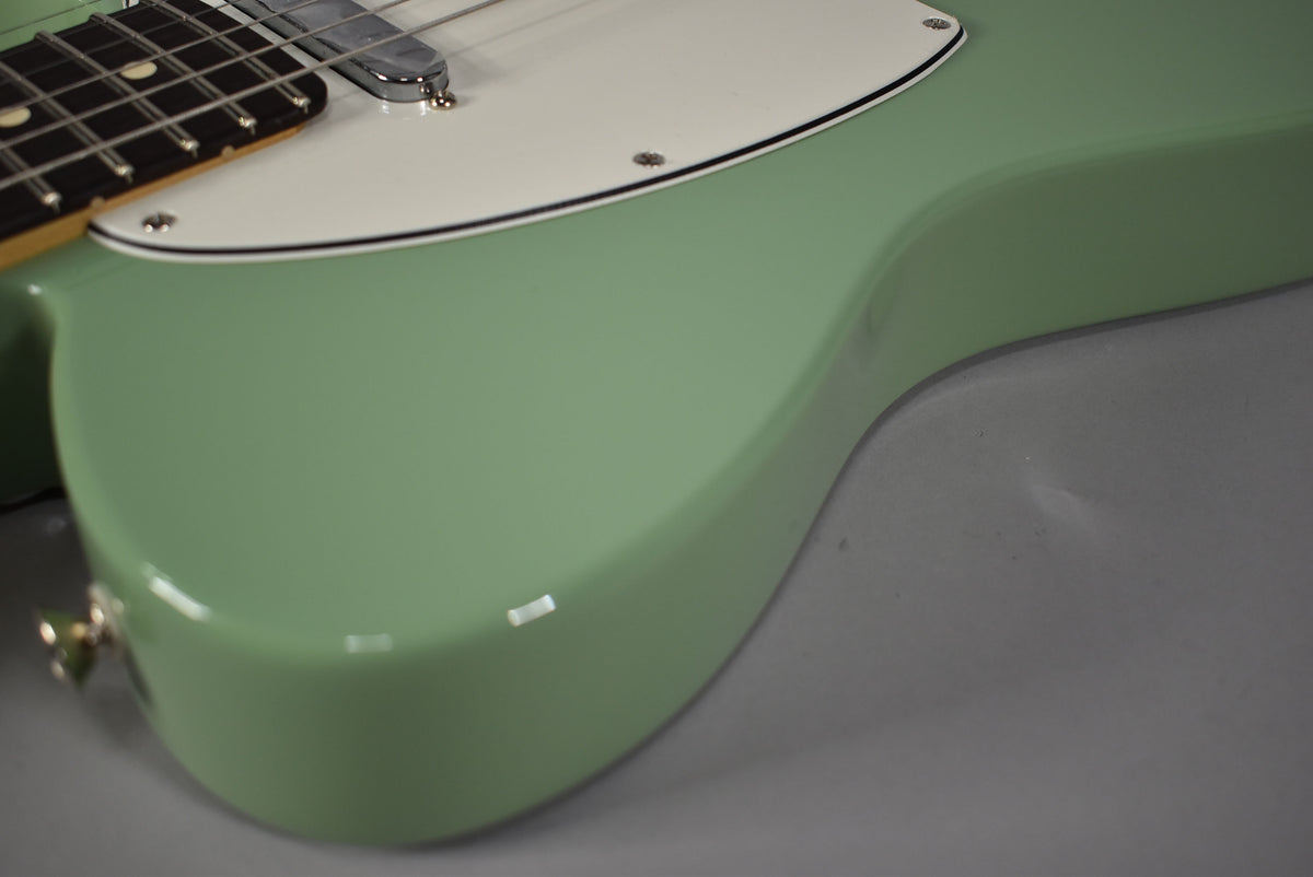 Close-up of the Telecaster's glossy birch green body, showing the lower bout, white pickguard, and part of the fretboard.