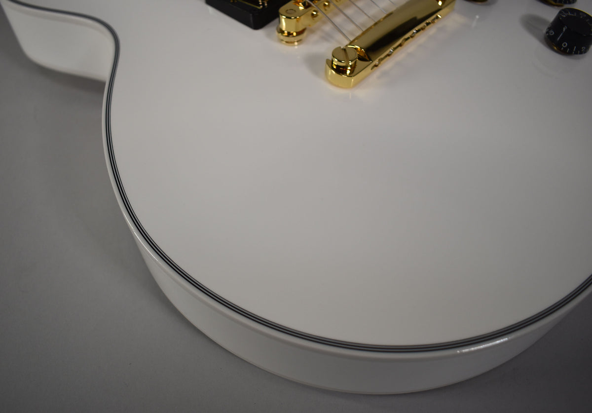 Close-up of the guitar's Alpine White body, showing the binding, gold bridge, and part of a black control knob.