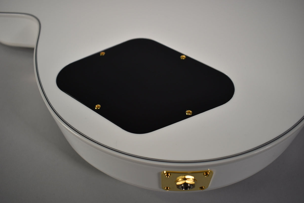 The back of an Alpine White Les Paul, showing the black control cavity cover with gold screws and a gold output jack.