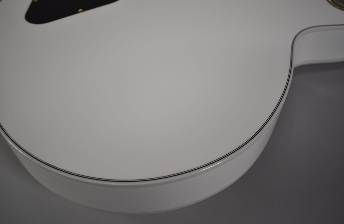 Close-up of the guitar's lower bout, showing the glossy Alpine White finish and black binding along the body's edge.