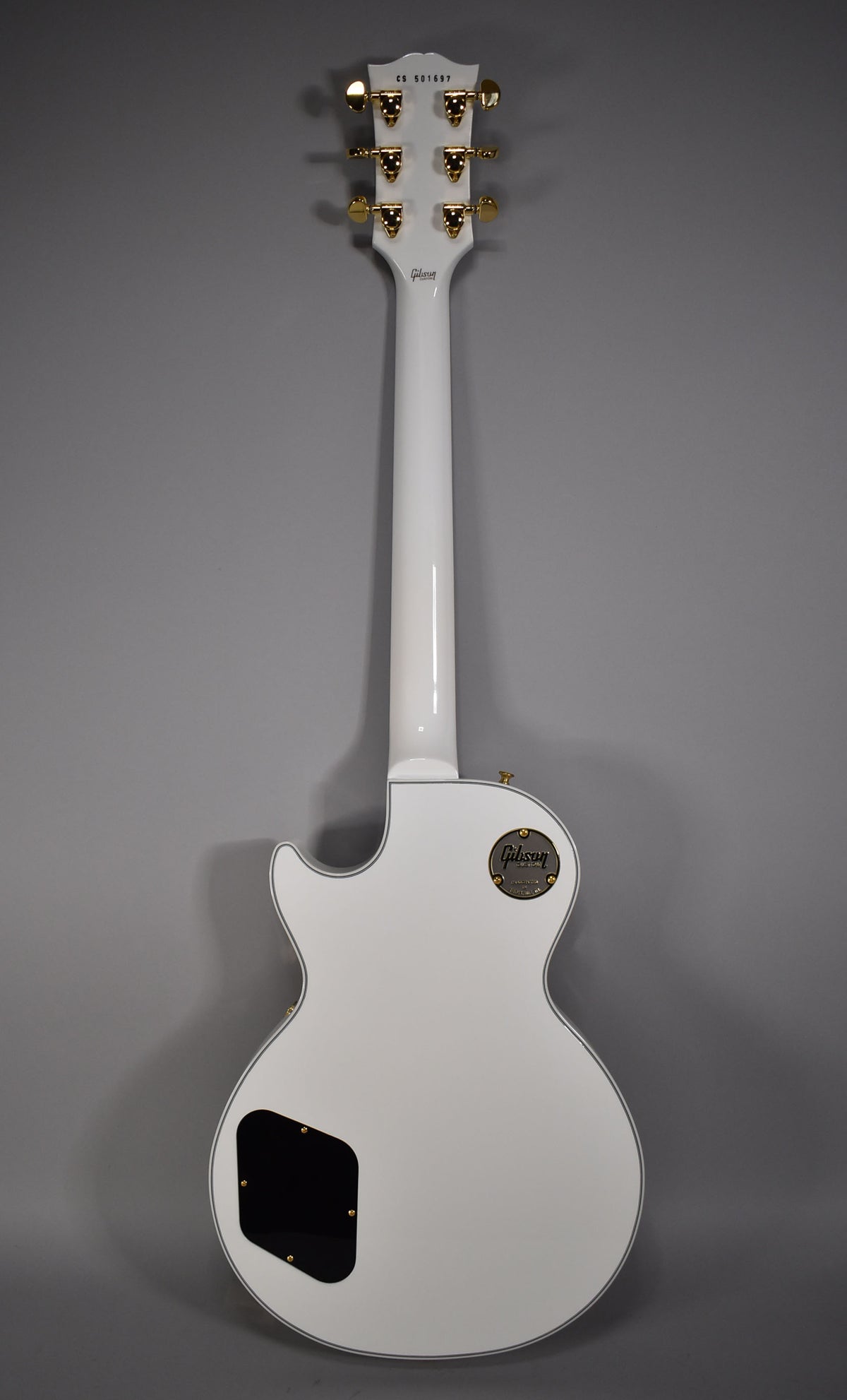 Full rear view of an Alpine White Les Paul with gold hardware, including tuners and a black control cavity cover.