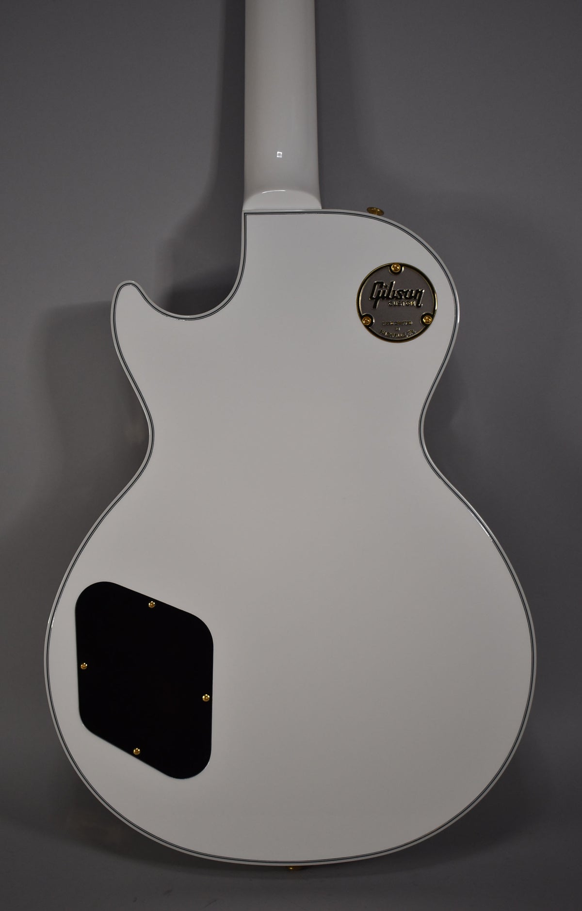 The back of an Alpine White Les Paul, showing the neck joint, control cavity cover, and a gold medallion.