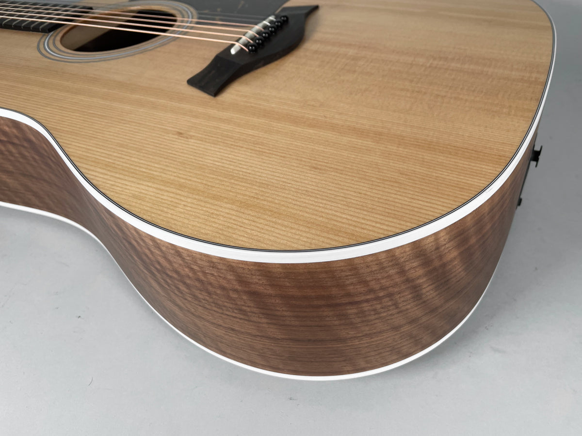 Close-up of the guitar's lower bout, showing the light natural wood top, dark wood sides, and white binding.