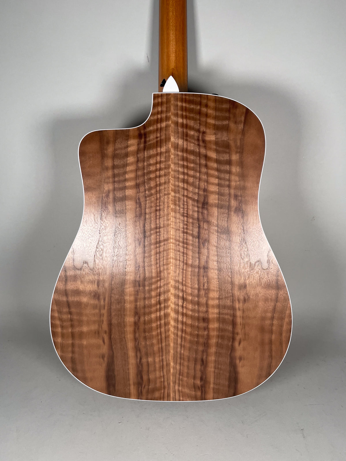 The guitar's back, with a cutaway, shows a rich, wavy brown wood grain and white binding, with a light brown neck visible at the top.