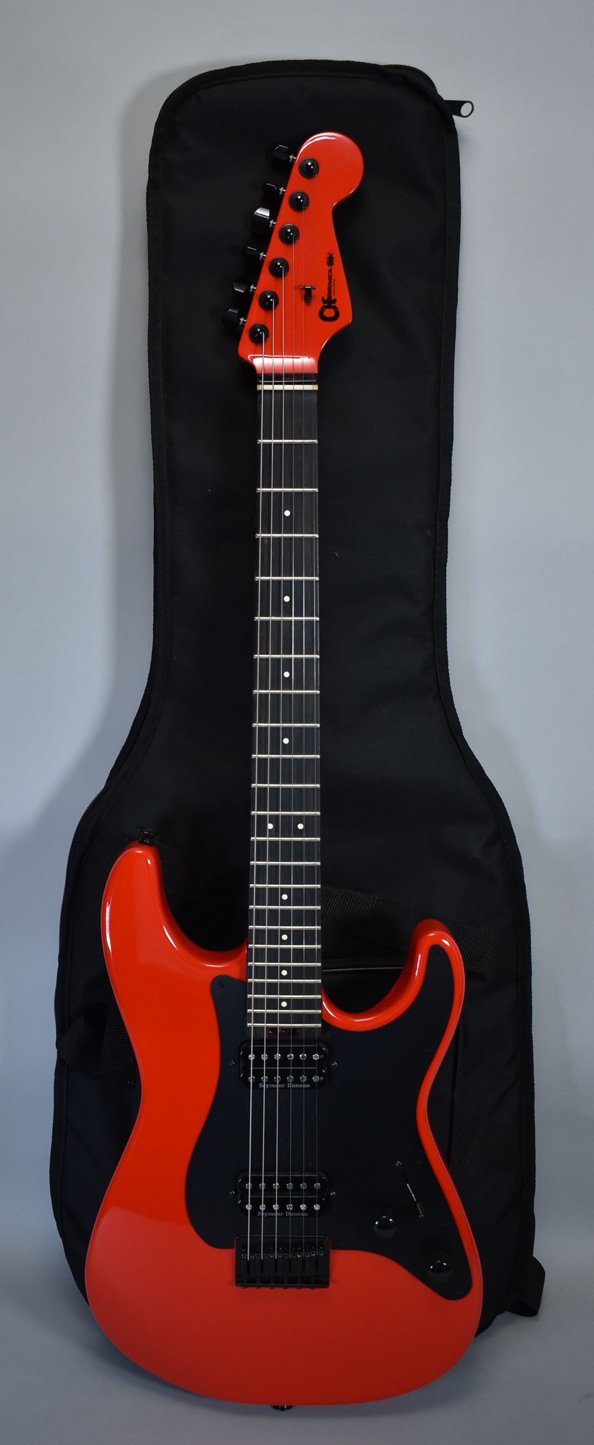 Full-length view of a glossy racing red electric guitar with a black pickguard, two humbuckers, and a matching red headstock.
