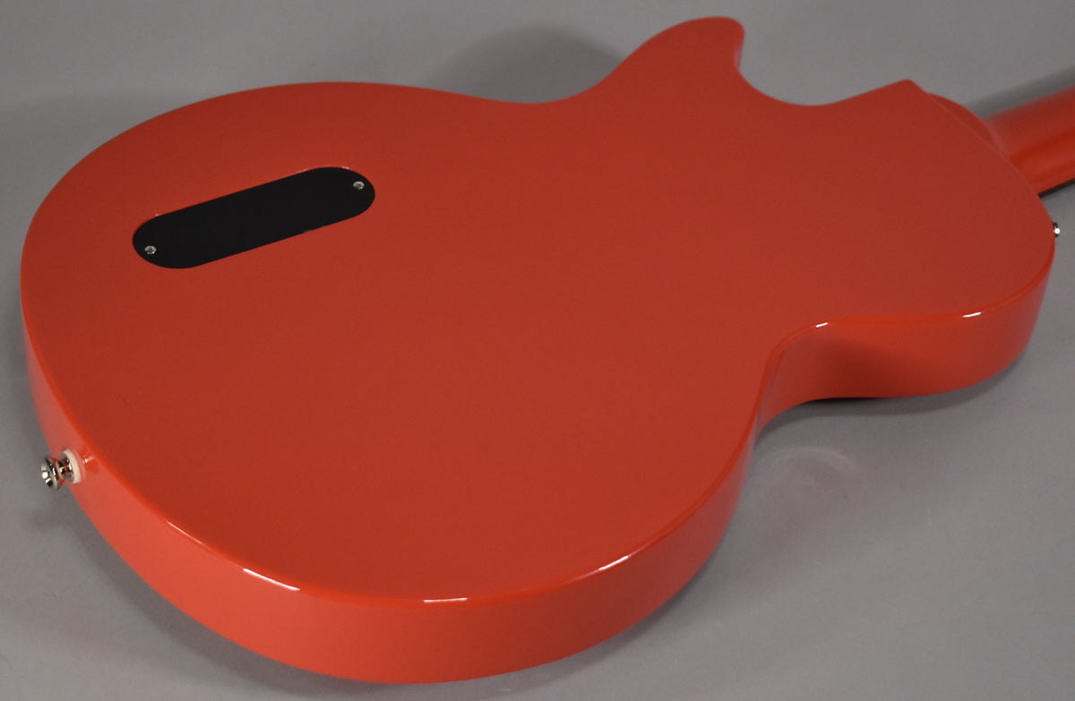 The back of the glossy radiant red guitar shows a black control cavity cover and a chrome strap button on the lower bout.