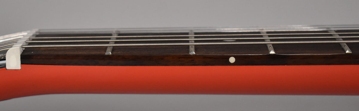 Close-up of the guitar's radiant red neck and dark fretboard with silver frets, strings, and a single white dot inlay.