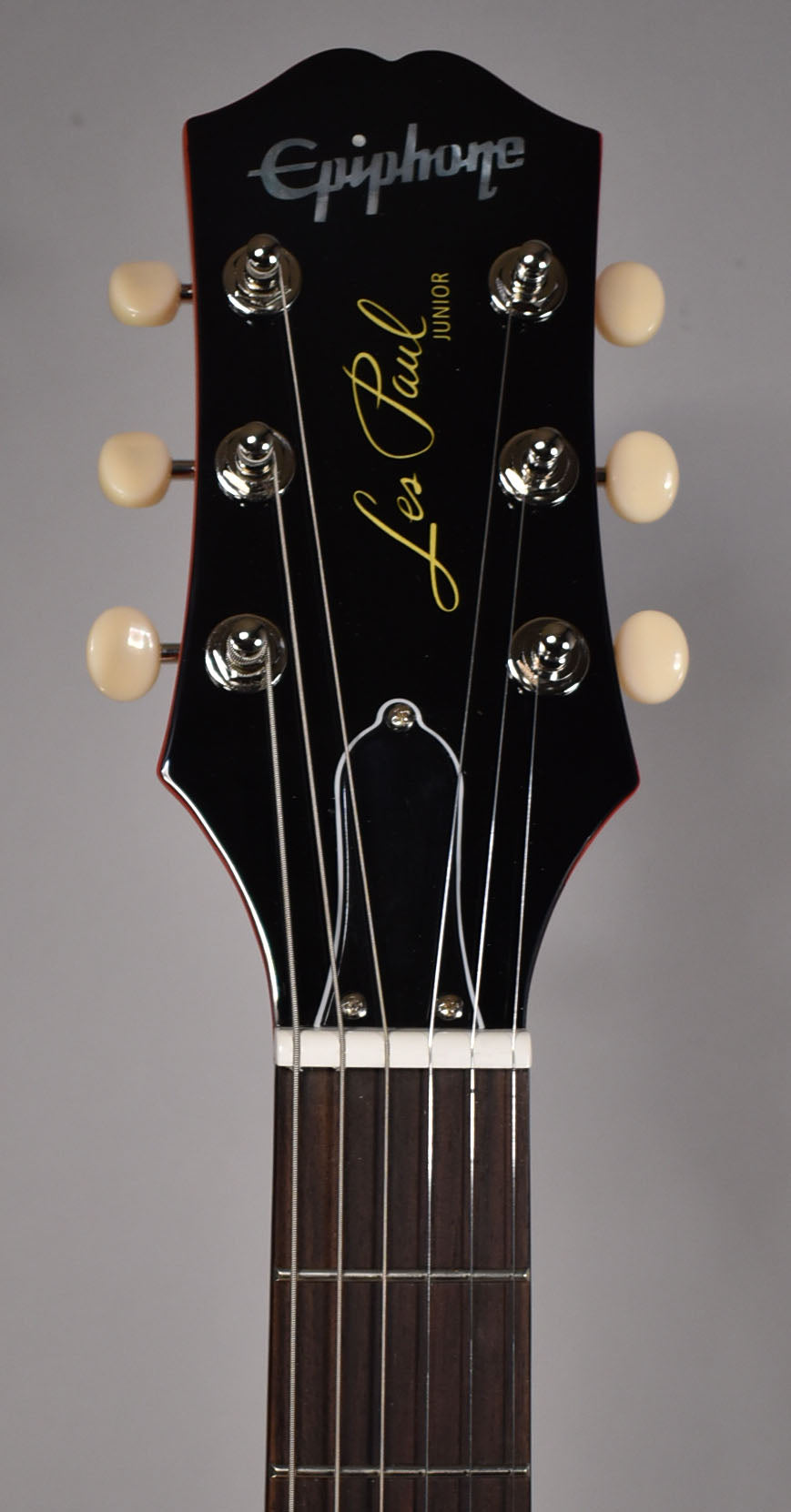 The guitar's headstock, black with a red edge, features six cream tuning pegs and a dark fretboard with a white nut.