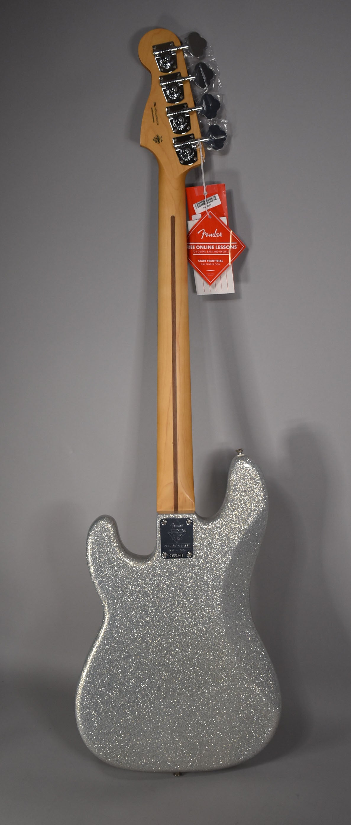 The bass is shown from the back, revealing a silver sparkle body, natural wood neck, and chrome tuning machines.