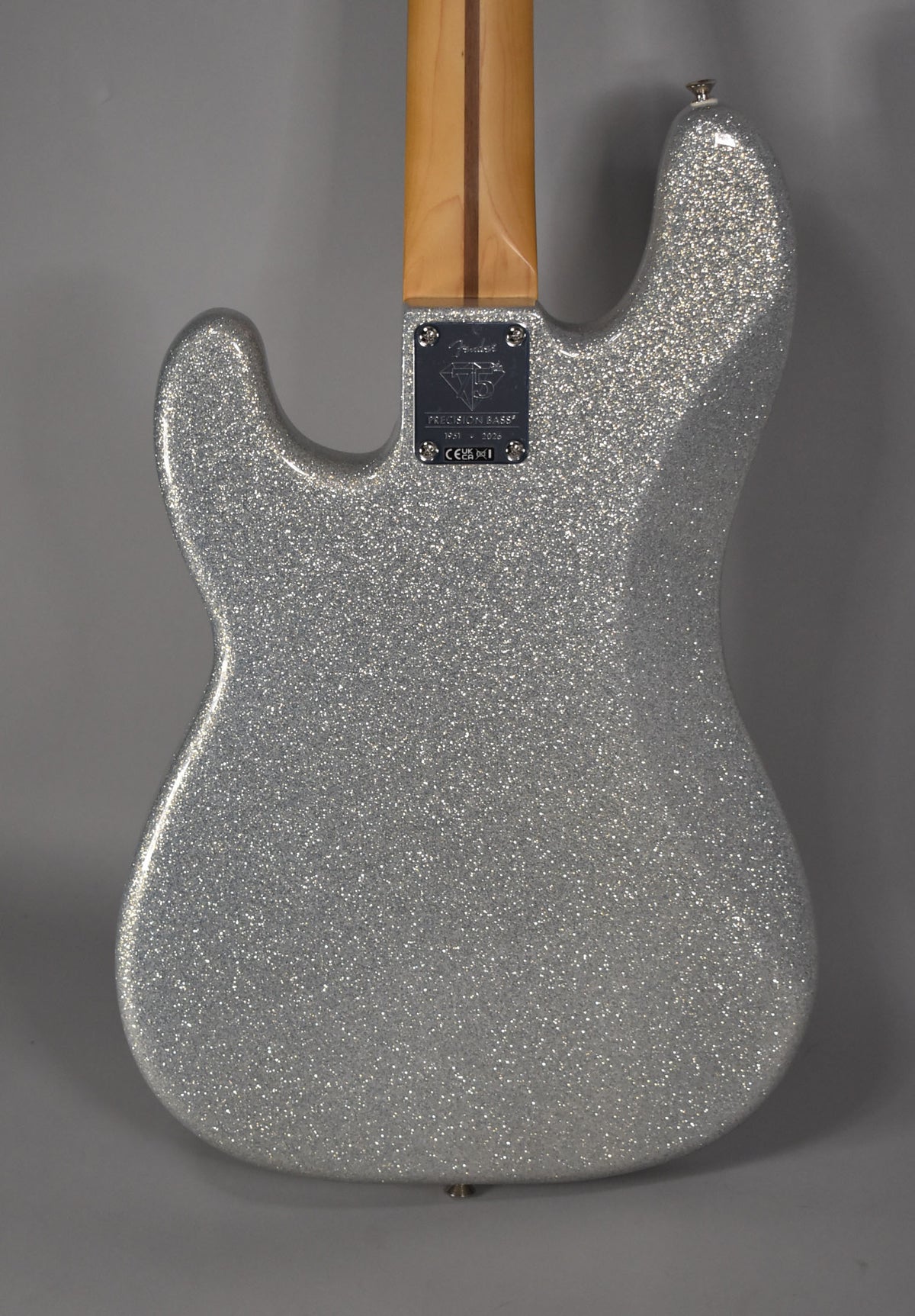 The bass's back is silver glitter, with a light wood neck and a dark metal neck plate.