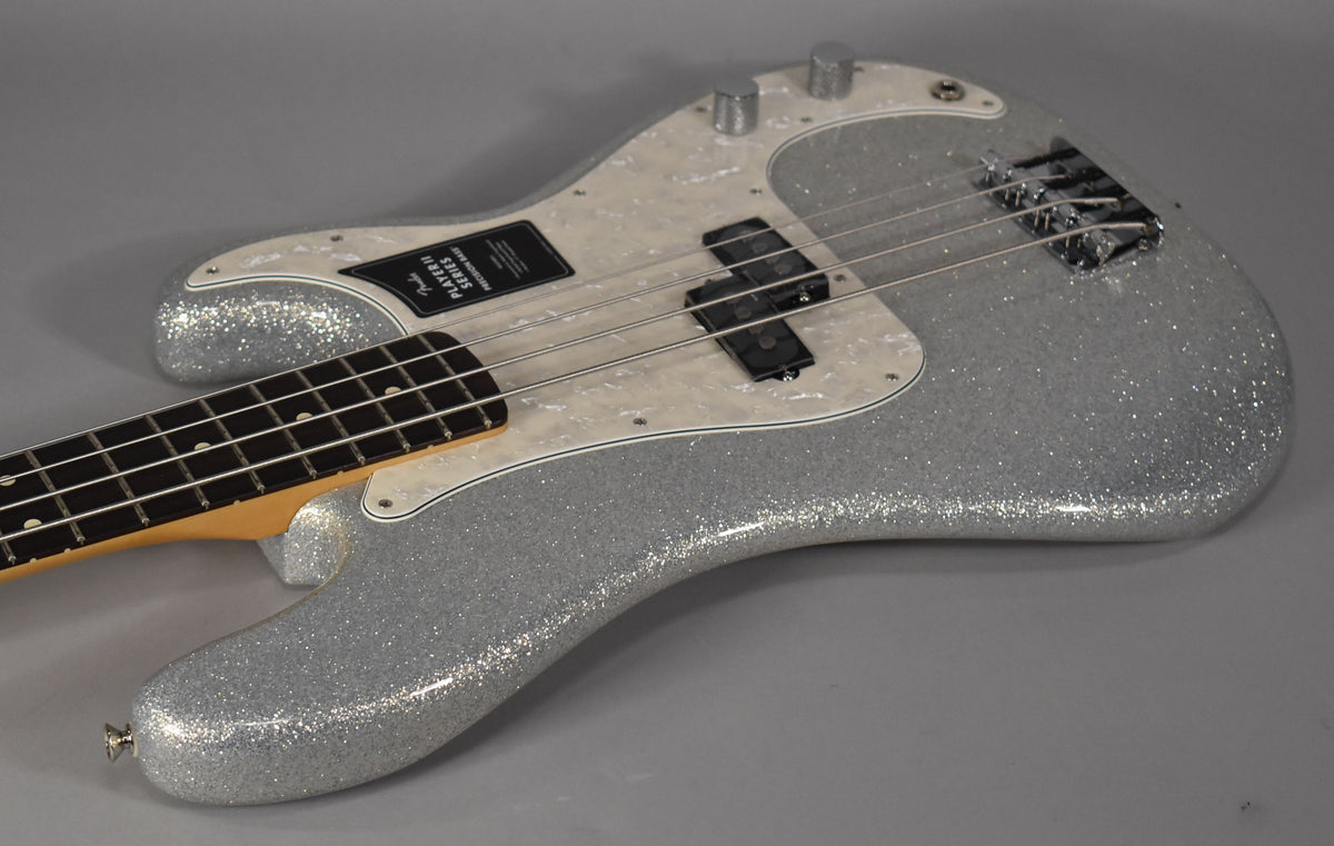 The silver sparkle bass is angled from the lower left, showing its pearloid pickguard, split pickup, and chrome hardware.