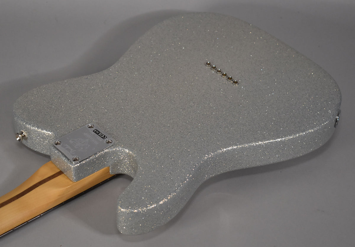The back of a silver sparkle Telecaster body, angled from the lower bout, shows a chrome neck plate and six string-through-body ferrules.