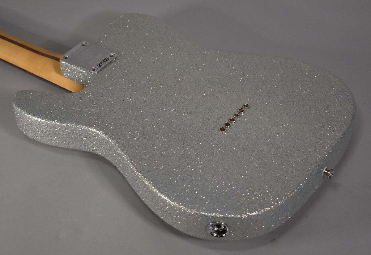 The back of a silver sparkle Telecaster body, angled from the neck joint to the output jack, showing six string-through-body ferrules.