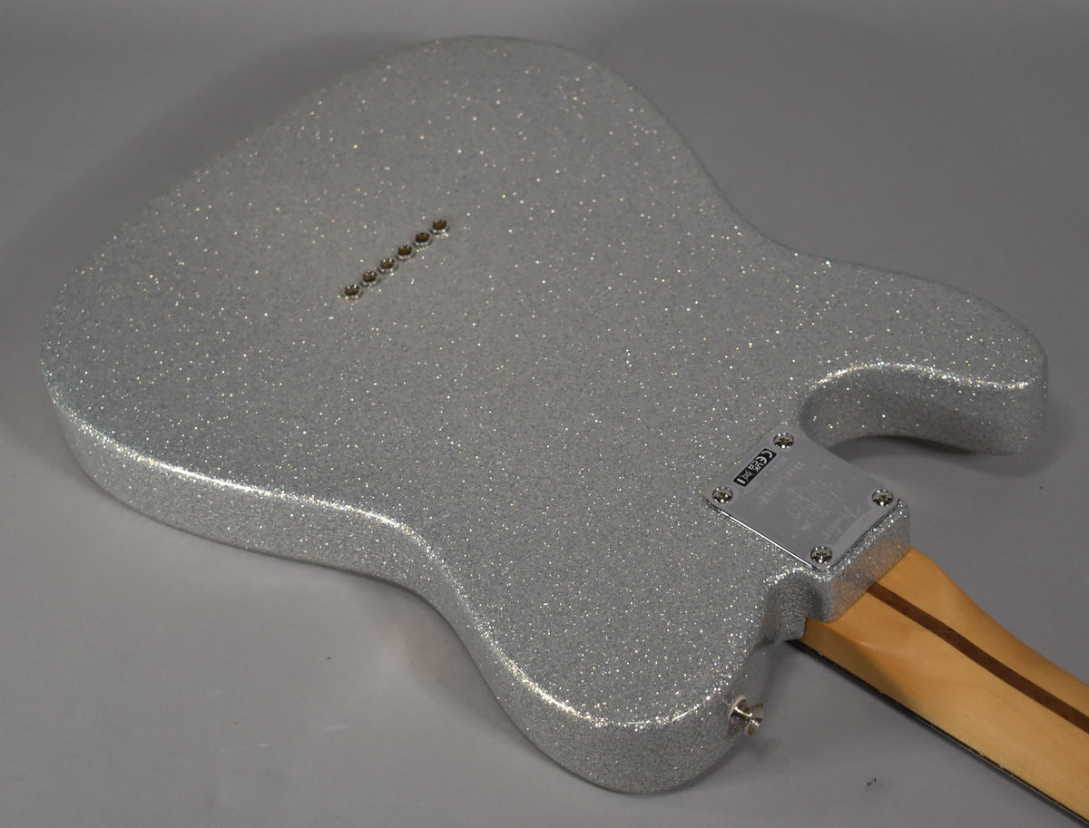The back of a silver sparkle Telecaster body, angled from the lower right, showing string-through ferrules and a chrome neck plate.