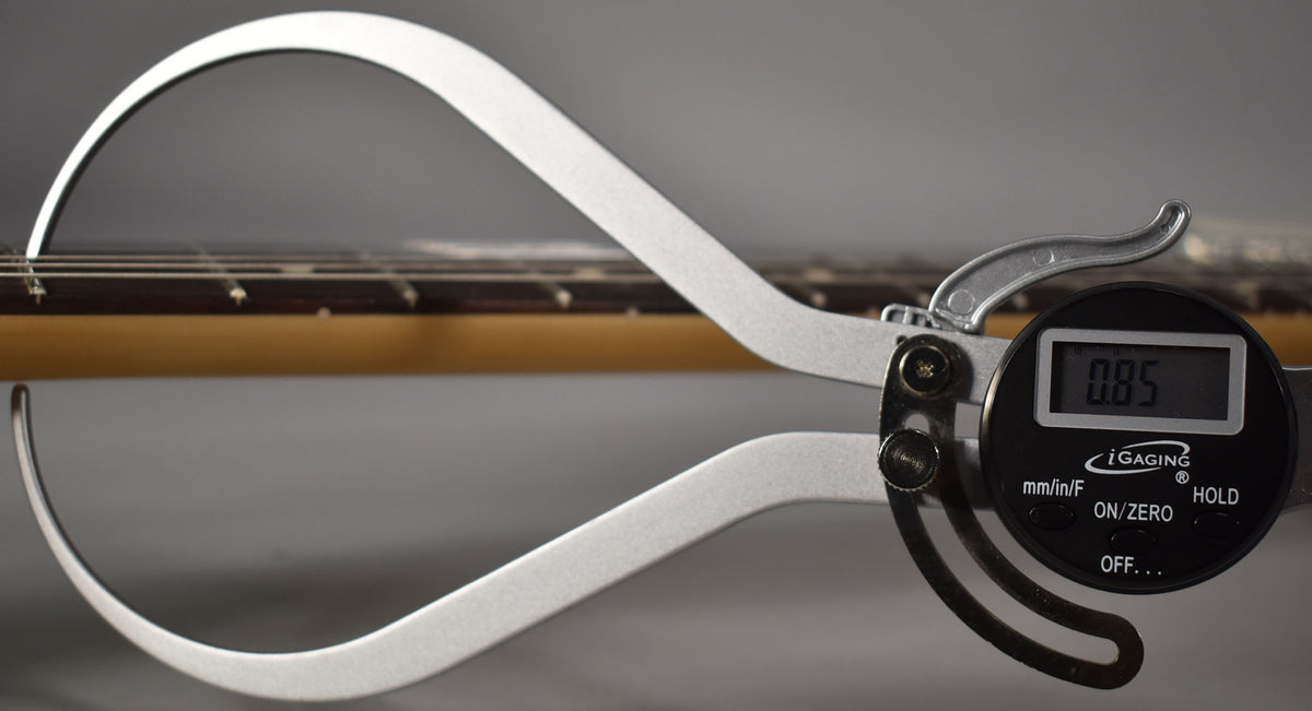 A digital caliper measures the string height on a Telecaster's rosewood fretboard, showing 0.85mm.