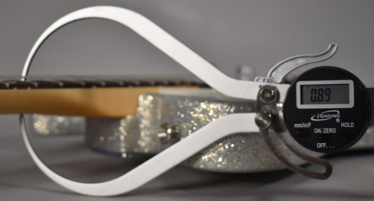 A digital caliper measures the fret height at 0.89mm, with the guitar's sparkle body visible below the neck.