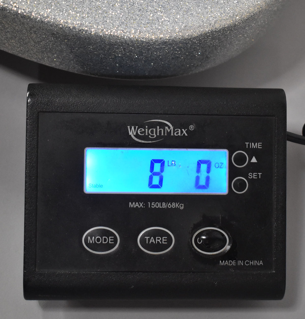 A digital scale displays "8 LB 0 OZ" with a glittery silver guitar body partially visible above it.