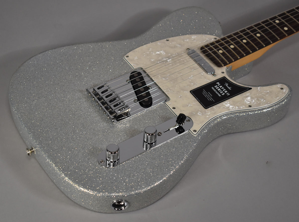 Silver sparkle Telecaster body, angled from the lower bout, showing a pearloid pickguard, chrome hardware, and a black hang tag.