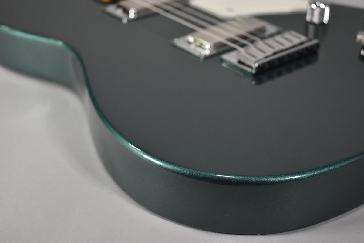 Close-up of the guitar's lower bout, showing the metallic Sherwood Green finish, chrome bridge, and a hint of the white pickguard.