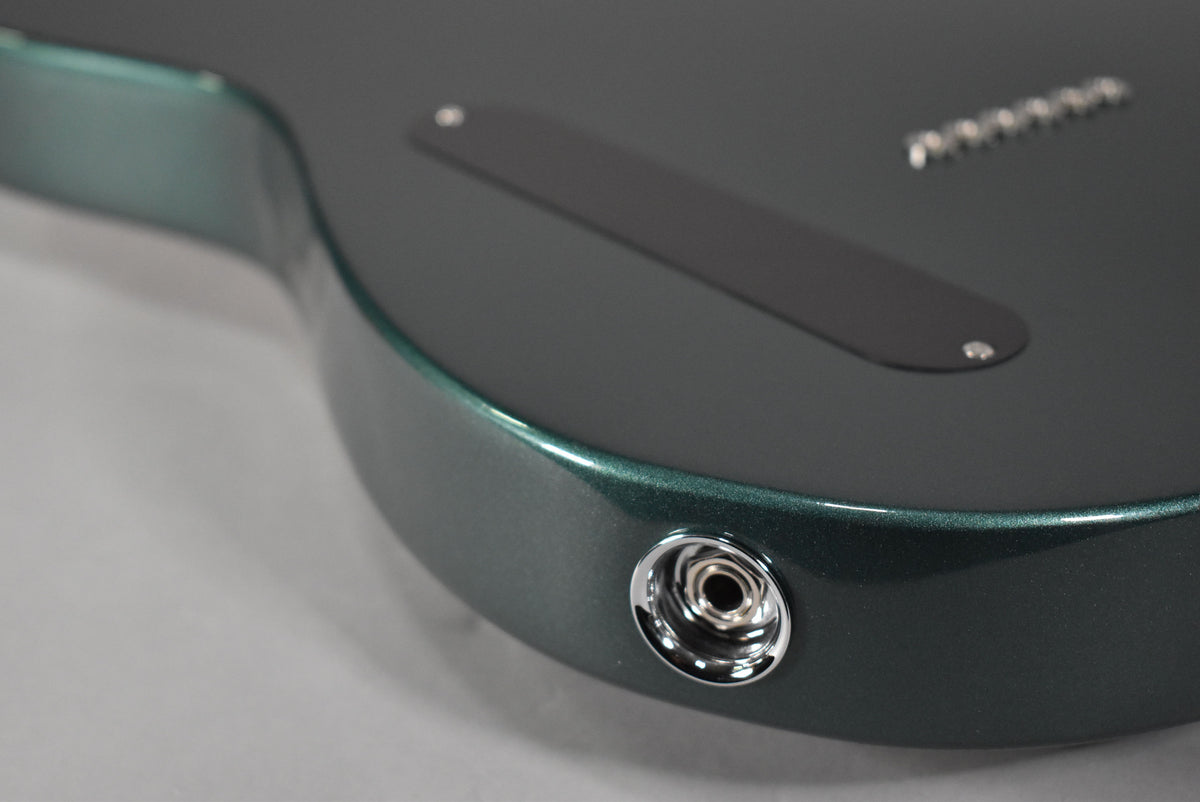 Close-up of the guitar's Sherwood Green metallic finish body, showing the chrome output jack and black string-through-body ferrule plate.