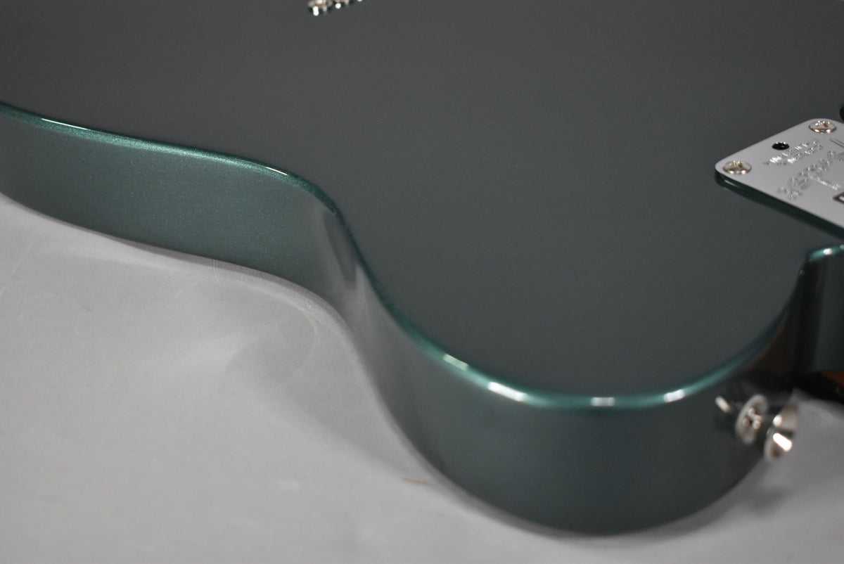The lower bout of a Sherwood Green metallic Telecaster body, showing the input jack and a chrome neck plate.