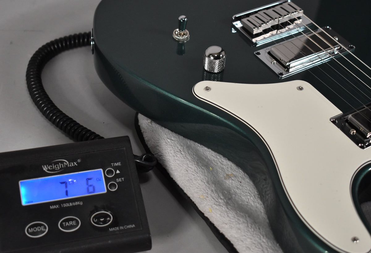 The Sherwood Green guitar body, with a white pickguard and chrome hardware, rests on a scale displaying 7 lbs 6 oz.