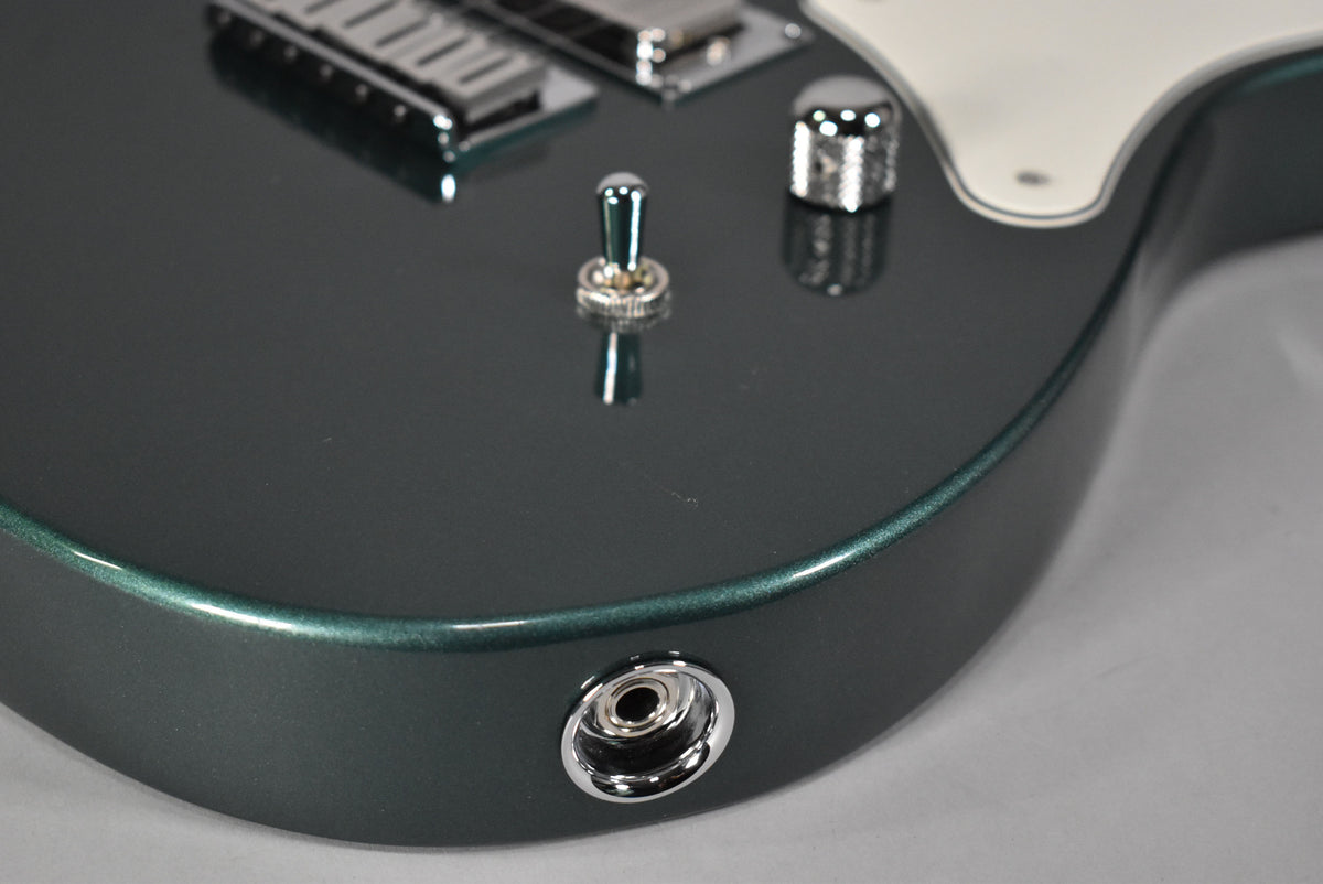 Close-up of the Sherwood Green metallic body, showing the chrome output jack, a toggle switch, and a volume knob.