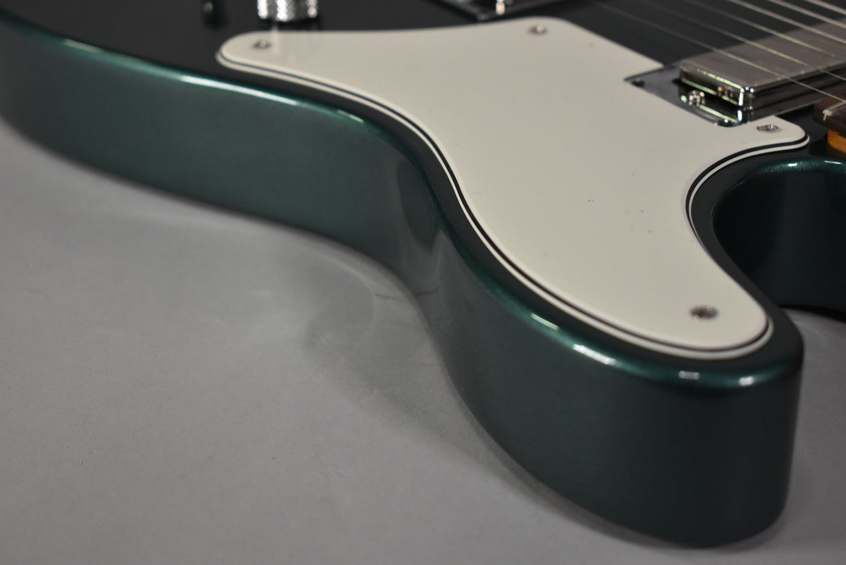 Close-up of the guitar's lower bout, showing the Sherwood Green metallic finish, cream pickguard with black pinstriping, and chrome bridge pickup.