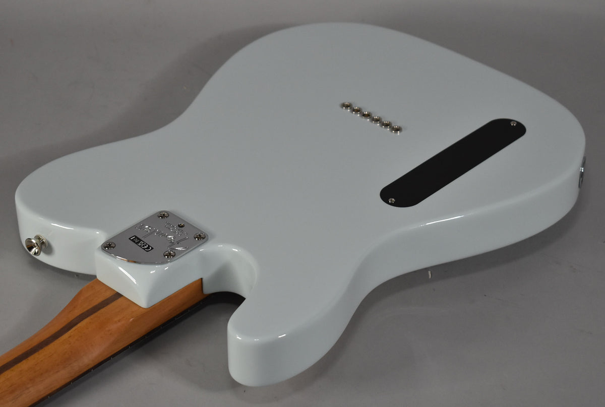 The back of a white Telecaster body, angled from the lower bout, showing the neck plate, string-through ferrules, and control cavity cover.