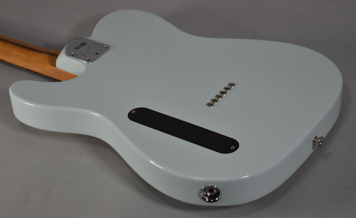 The back of a light blue Telecaster body, showing the neck plate, string ferrules, and a black control cavity cover.