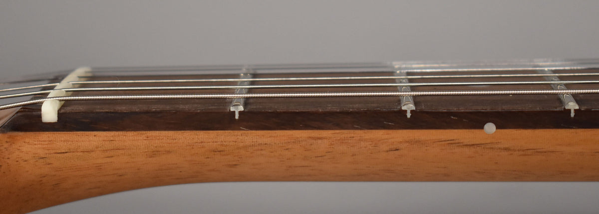 Close-up of the guitar's neck from the side, showing a dark rosewood fretboard, light maple neck, and a white nut.