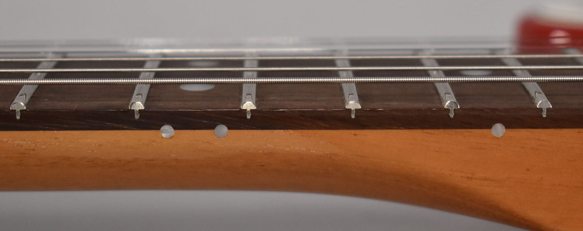 Close-up of the dark rosewood fretboard and light maple neck, showing five frets, strings, and three white side dot markers.