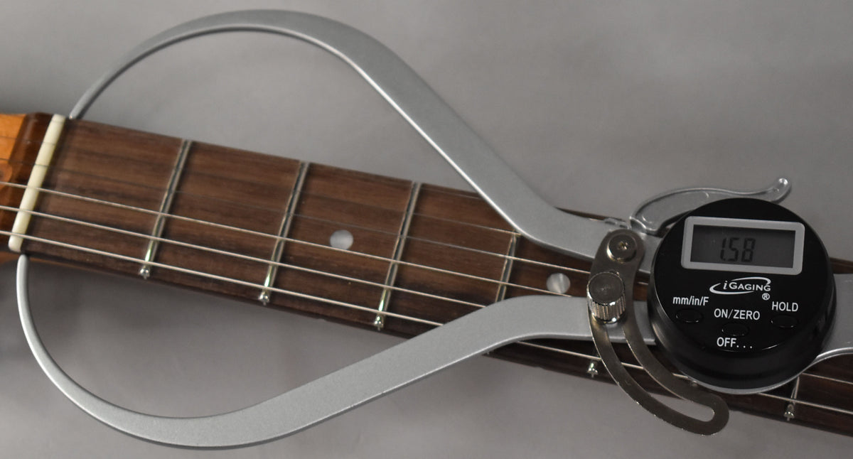 Close-up of the dark rosewood fretboard with a digital caliper measuring the fret height at 1.58mm.