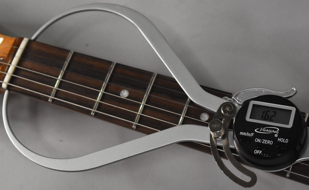 Close-up of the dark rosewood fretboard with a digital fret height gauge showing 1.62mm on the 5th fret.