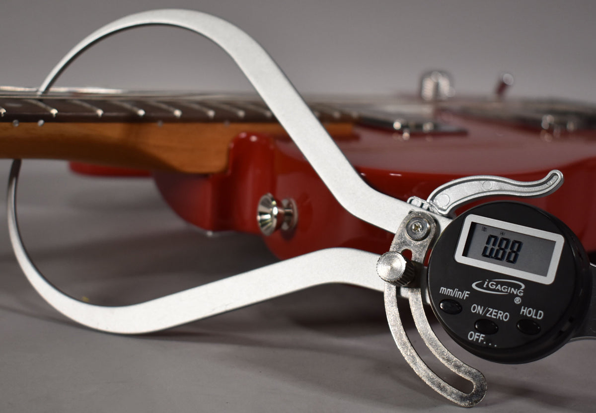 A digital caliper measures the fret height on the dark rosewood fretboard of the glossy red Telecaster.