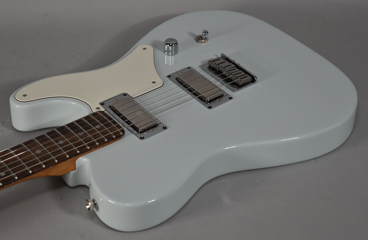 Light blue solid body electric guitar, angled from the neck joint, with two chrome humbuckers and a cream pickguard.