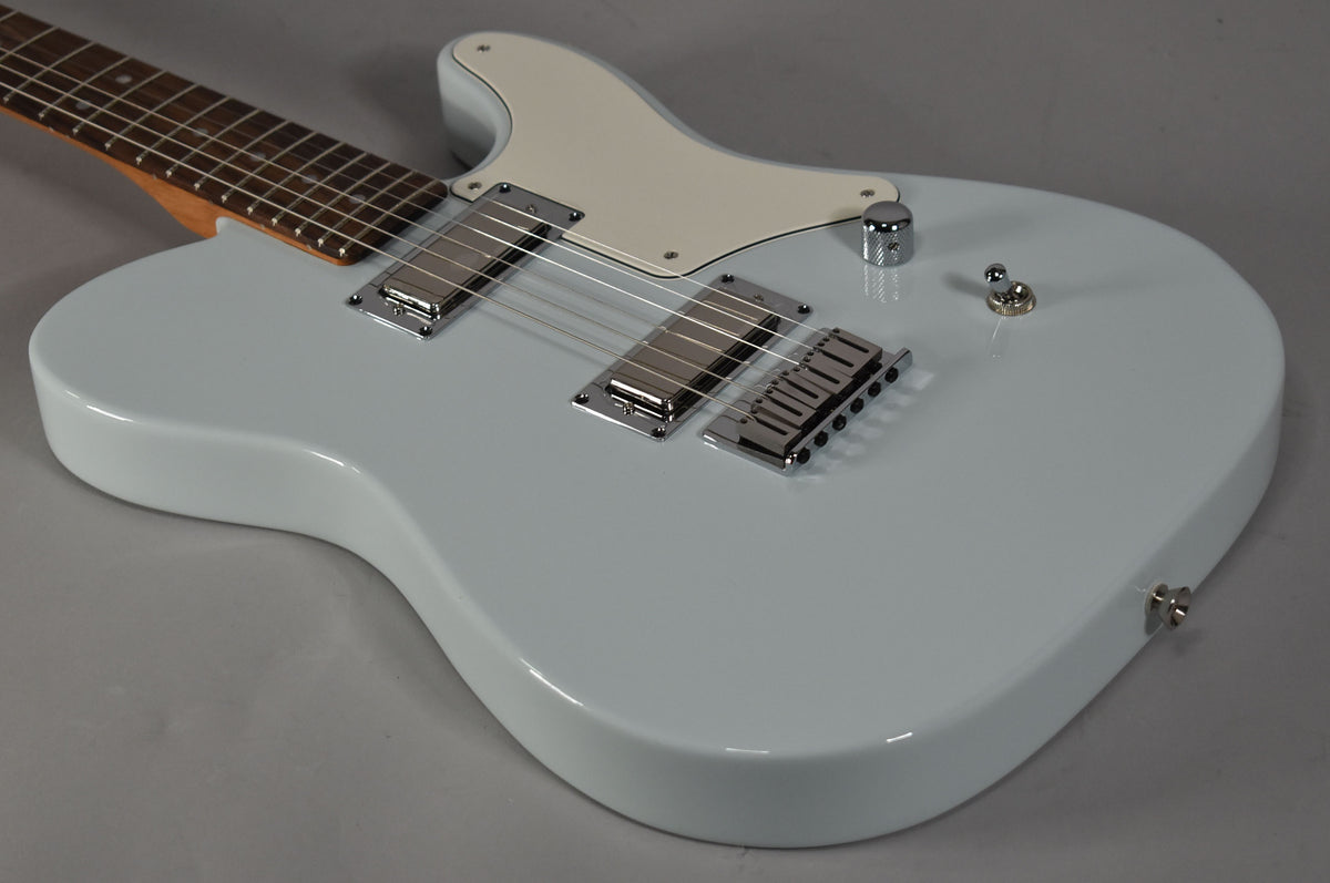The light blue solid-body electric guitar is angled from the upper left, showing its cream pickguard, two chrome humbuckers, and a single chrome knob.