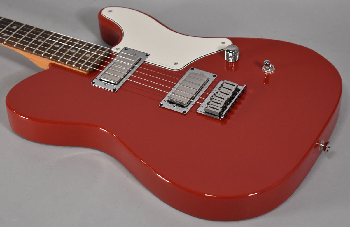 The cherry red guitar, angled from the neck, features a white pickguard, two chrome humbuckers, a chrome bridge, and a single knurled control knob.