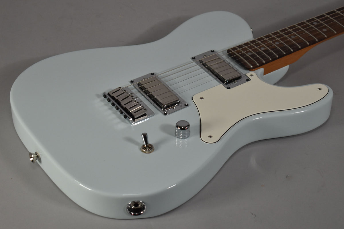 Light blue solid body electric guitar, angled from above, showing two chrome humbuckers, a cream pickguard, and a single chrome knob.