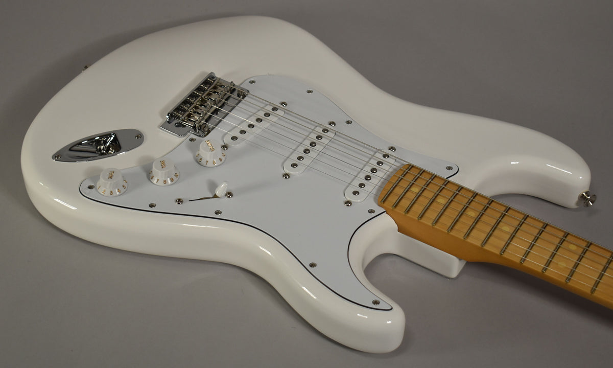 Polar white Stratocaster body, angled from above, showing the white pickguard, three single-coil pickups, chrome bridge, and maple fretboard.
