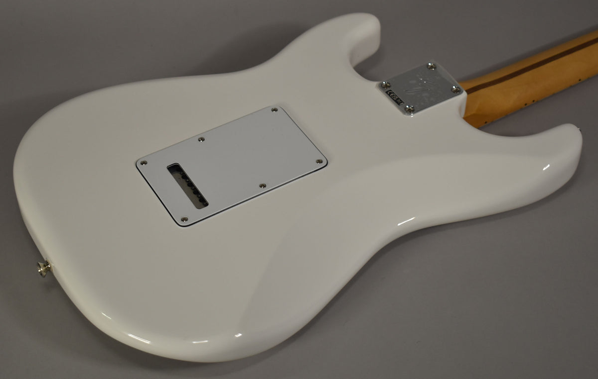 The back of a glossy white Stratocaster body, angled from the lower left, shows a white tremolo cover and a chrome neck plate.