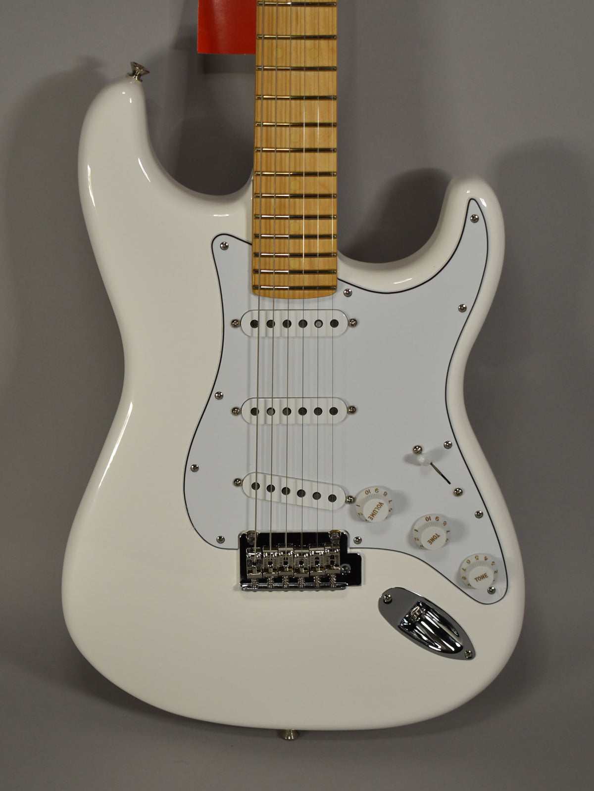 Full-body view of a glossy white Stratocaster with a white pickguard, three single-coil pickups, chrome hardware, and a maple fretboard.
