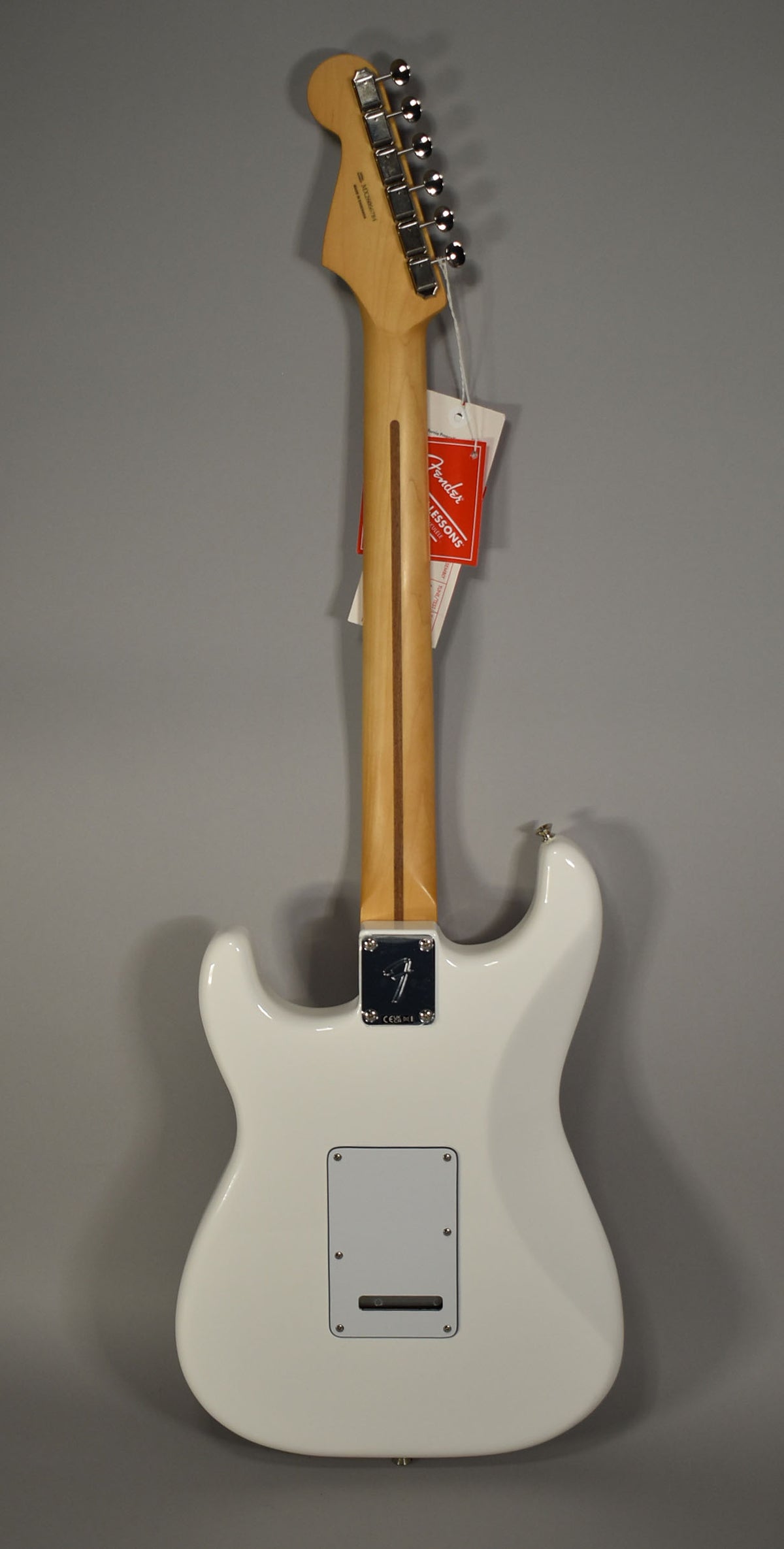 Full rear view of a glossy white Stratocaster with a light maple neck, chrome tuners, and a rectangular backplate.