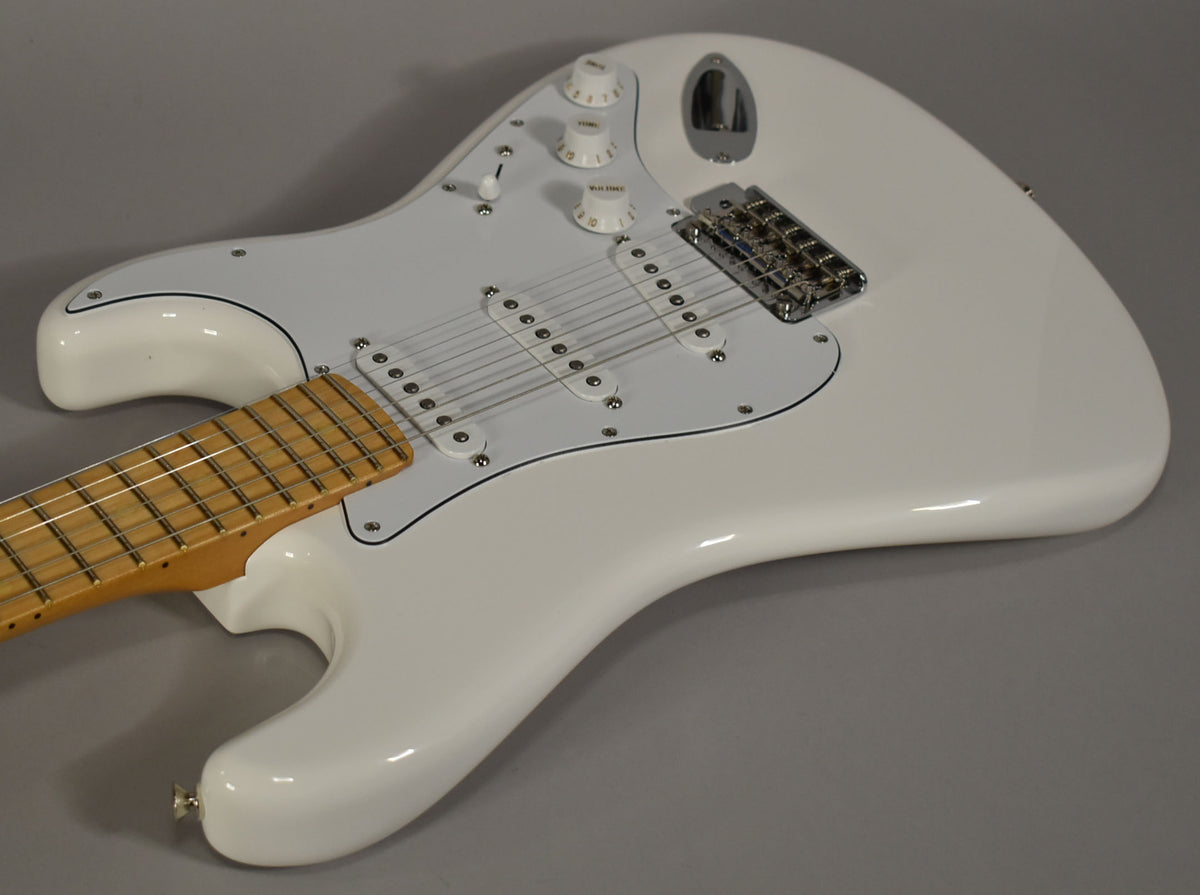 The Polar White Stratocaster's body and maple neck are angled from the lower left, showing the white pickguard, three single-coil pickups, and chrome hardware.