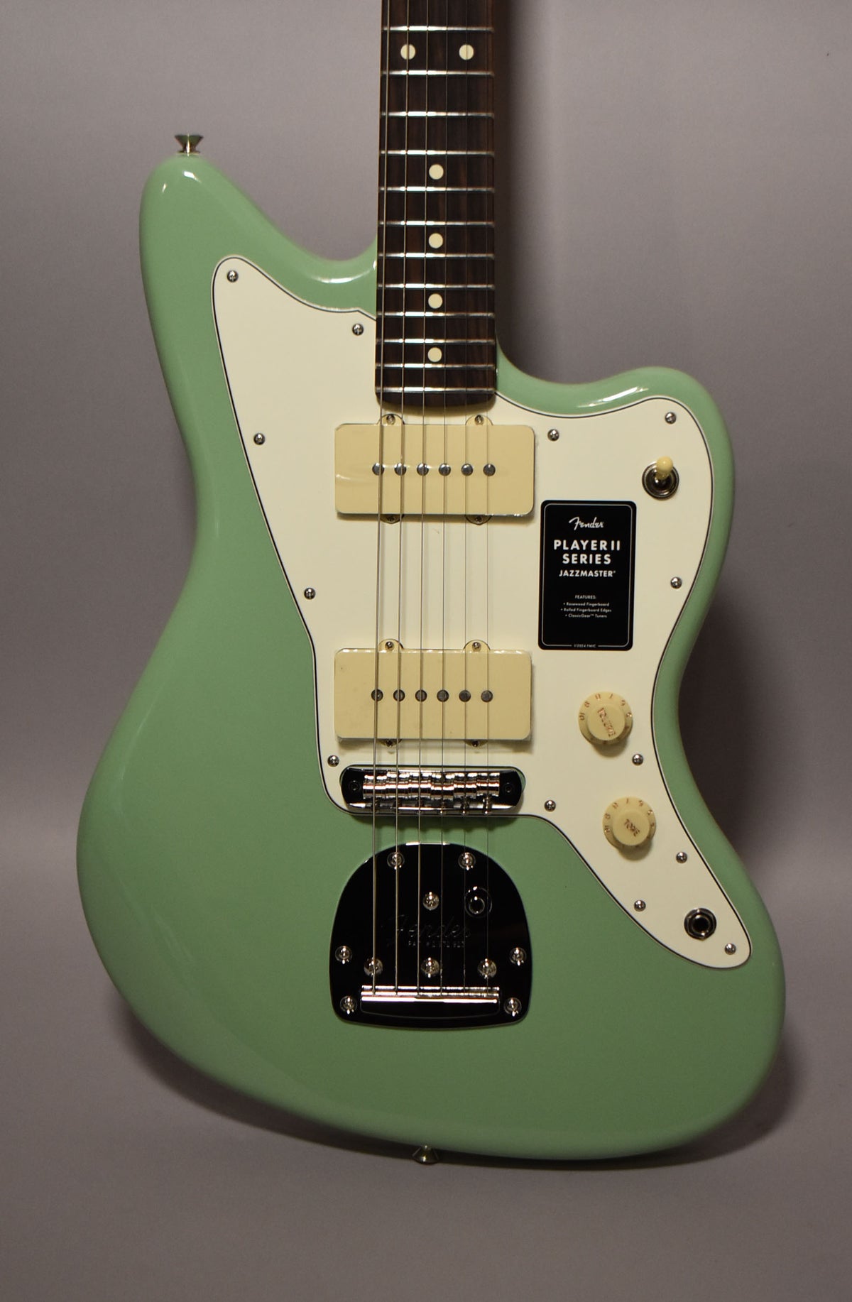 Full-frame view of a glossy birch green Jazzmaster with an off-white pickguard, two cream P90 pickups, and chrome hardware.