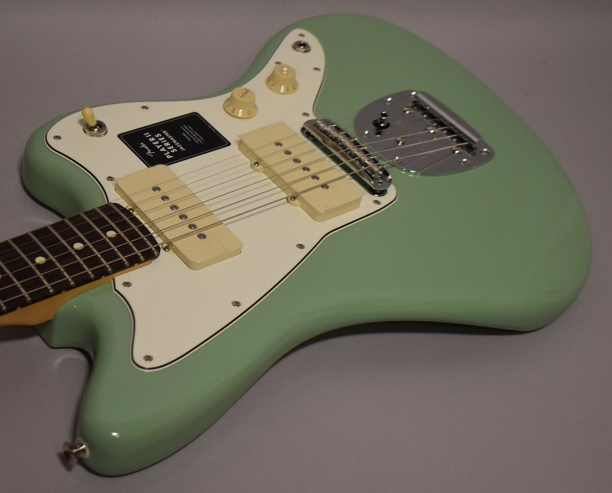Angled view of a mint green Jazzmaster body with an off-white pickguard, two cream P90-style pickups, and chrome bridge.